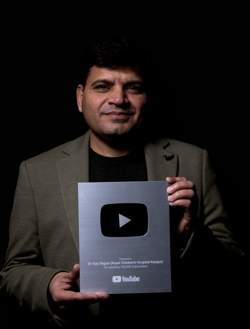 Dr. Ajay Bajpai holding the YouTube Silver Play Button for 100,000 subscribers