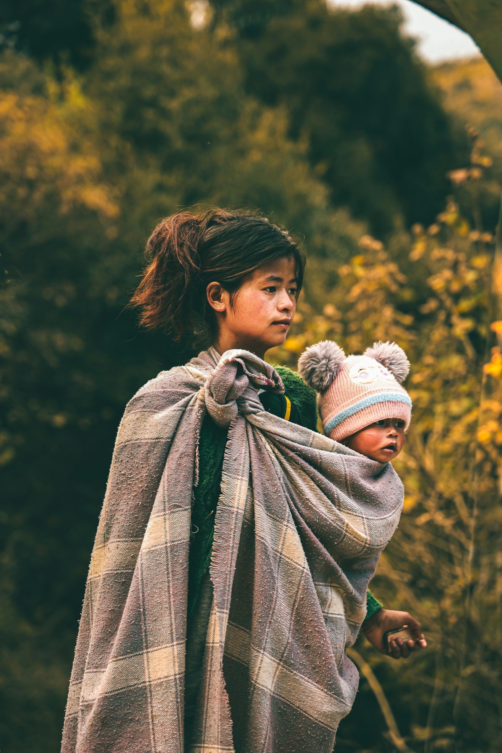Young girl holding a baby wrapped in a blanket